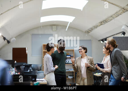 Multi-ethnic group of business people talking pendant pause café en souriant gaiement, tandis qu'office copy space Banque D'Images