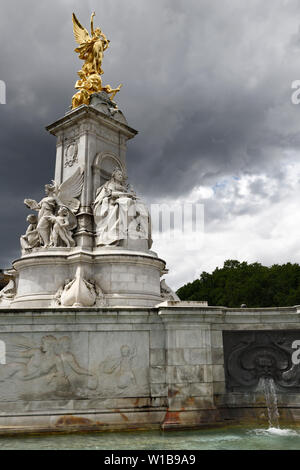 Victoria Memorial monument à la reine Victoria et la fontaine au centre commercial, le palais de Buckingham avec de l'or La Victoire de Samothrace et de sombres nuages London England Banque D'Images