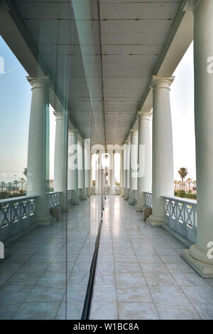 Un corridor extérieur donnant sur la mer d'un bâtiment classique avec des colonnes blanches reflètent dans un verre. Banque D'Images