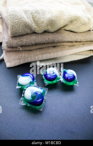 Jour de lessive - lessive lessive gousses sur une table pliante avec tan de serviettes. Banque D'Images