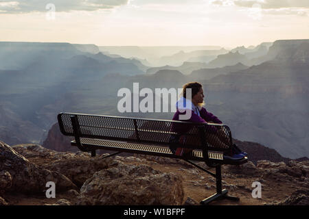 De race blanche, aux cheveux bouclés profil femme touristiques regardant le coucher du soleil à partir d'un banc à Desert View, le Parc National du Grand Canyon, Arizona, USA Banque D'Images