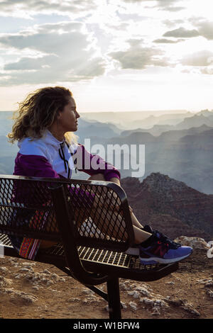 De race blanche, aux cheveux bouclés profil femme touristiques regardant le coucher du soleil à partir d'un banc à Desert View, le Parc National du Grand Canyon, Arizona, USA Banque D'Images