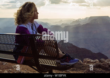 De race blanche, aux cheveux bouclés profil femme touristiques regardant le coucher du soleil à partir d'un banc à Desert View, le Parc National du Grand Canyon, Arizona, USA Banque D'Images