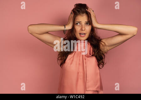 Jeune femme brune à la tête des embrayages à fond rose, Banque D'Images