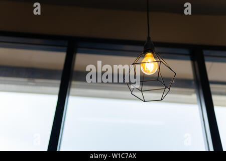 Ampoule dans la cage d'acier noir accrocher au plafond dans un café, la mode et la lampe dans un style moderne. Banque D'Images