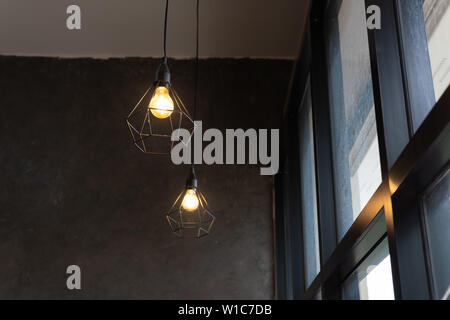 Ampoule dans la cage d'acier noir accrocher au plafond dans un café, la mode et la lampe dans un style moderne. Banque D'Images