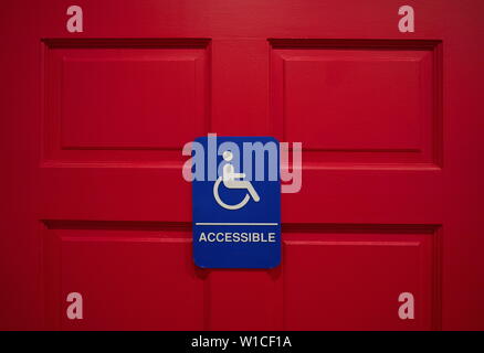 Un handicap ou un marqueur signe bleu monté sur un rouge profond porte des toilettes. Banque D'Images