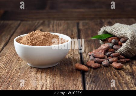 La poudre de cacao et les grains de cacao sur fond de bois Banque D'Images