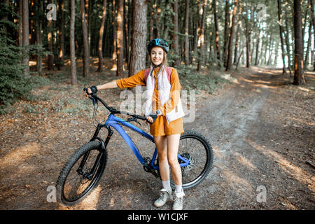 Portrait d'une jeune femme avec des vélos de montagne dans la forêt Banque D'Images