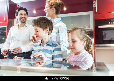 Les enfants de la nouvelle cuisine leurs parents sont sur le point d'acheter Banque D'Images