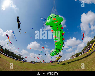 Pasir Gudang, Malaisie - 1 mars, 2019 : Soft kite représentant une larve verte volant à la 24e mondiale Pasir Gudang Kite Festival avec les participants à partir de 4 Banque D'Images