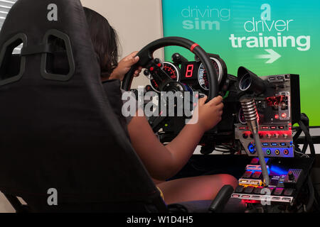 Une jeune personne assise dans un cockpit de course et la sélection de la formation de pilote à partir de l'écran de jeu tout en tenant le volant. Banque D'Images