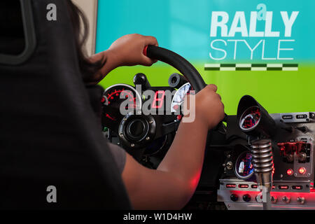 Une fille jouant un jeu de rallye tenant un volant de course d'une carte sim de pilotage et tourner le volant vers la droite. Banque D'Images