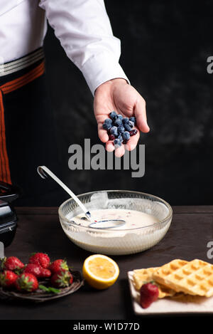 L'ajout de chef des fruits dans la pâte à gaufres close up Banque D'Images