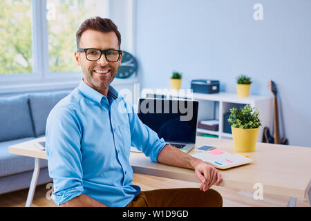 Handsome man sitting in office and smiling at camera Banque D'Images