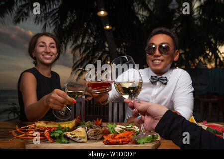 Amis dans un restaurant de fruits de mer - cheers clink glasses Banque D'Images
