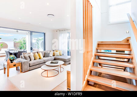 Salon élégant attaché à la galerie coulissante avec portes en verre français, à côté d'un escalier en bois. Banque D'Images