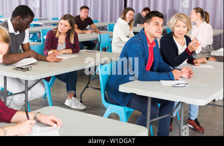 Groupe d'étudiants adultes multinationale de discuter les sujets des leçons dans l'auditorium Banque D'Images