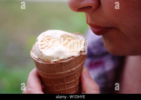 La fille mange la crème glacée qui fond rapidement dans une gaufre Cup. Banque D'Images