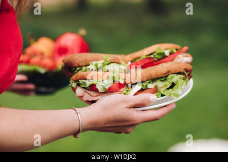 Femme portant des sandwichs frais. Close-up of woman carrying méconnaissable de délicieux sandwiches faits maison sur plaques. pain, tomates, salade, viande de porc. Banque D'Images