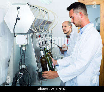 Portrait of young male winery travailleur en uniforme avec des machines d'embouteillage sur factory Banque D'Images