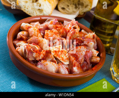 Des tapas espagnoles. Couper les oreilles de porc rôti servi avec paprika fumée en cuvette d'argile Banque D'Images