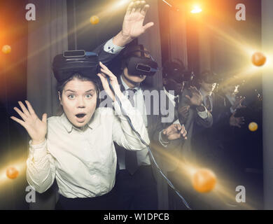 Portrait de jeune fille et ses collègues portant des lunettes de réalité virtuelle dans la salle d'animations Banque D'Images