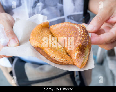 Main tenant l'alimentation de rue, Indonésien, le martabak doux crêpe traditionnelle de près. Banque D'Images