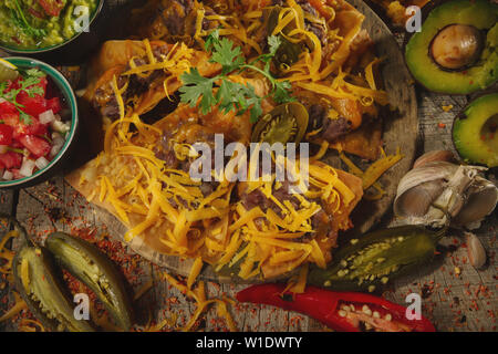 Dîner de style mexicain avec des herbes tortilla chips de maïs nachos au fromage, salsa, Sel et piment d'guakomole a servi plus de tables en bois. Banque D'Images