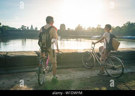 Couple de touristes à vélo dans le temple d'Angkor, au Cambodge. Angkor Wat façade principale reflétée sur l'eau étang. Eco friendly tourisme voyage. Tonique Banque D'Images