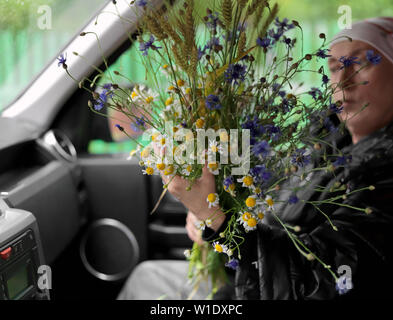 Domaine des fleurs dans les mains d'une femme, assis sur le siège passager, concept d'événements Banque D'Images