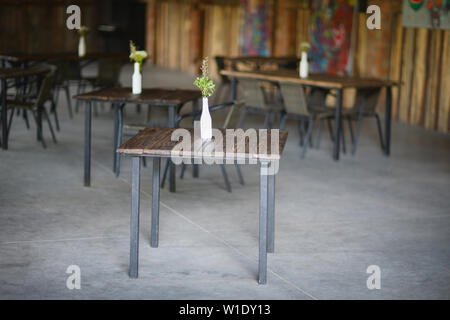 Vert lumineux bouquets de fleurs sauvages dans un vases stylisés bouteilles sur les tables de café Banque D'Images