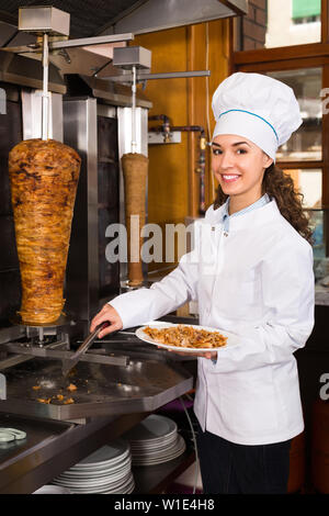 Souriante jeune femme chef de la viande d'agneau coupe shawarma Banque D'Images