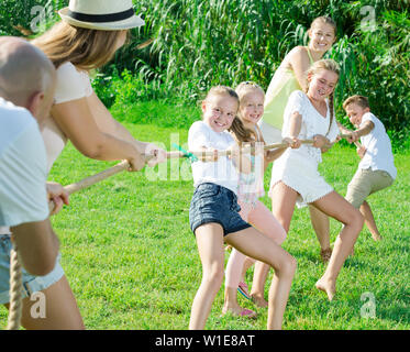 Les enfants avec les parents jouer remorqueur de la guerre durant les jeux en plein air aux beaux jours Banque D'Images