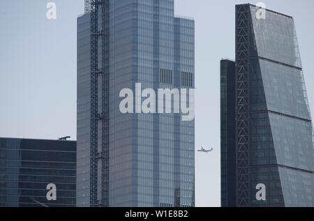 Londres, Royaume-Uni. 2 juillet 2019. Au chaud pour la journée dans le centre de Londres, un avion s'approche de l'aéroport de London Docklands vu par l'intermédiaire de l'office des gratte-ciel à 122 Leadenhall Street ('l'Cheesegrater') et 22 Bishopsgate (vingt) dans la ville de Londres. Credit : Malcolm Park/Alamy Live News. Banque D'Images