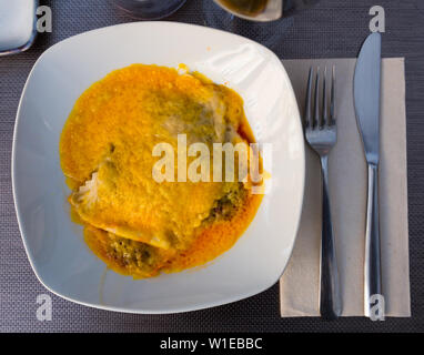 Vue de dessus de la tranche de viande traditionnelles lasagnes à la béchamel garnie de fromage râpé servi sur plaque blanche Banque D'Images