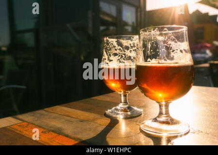 Libre de deux verres de bière sur terrasse avec table soir soleil qui brille à travers eux. Relaxation, nourriture et boisson concept avec copie espace. Banque D'Images