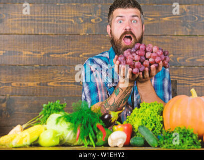 Récolte de chez nous avec l'agriculteur sur la table. Farmer fiers de récolter les légumes et les raisins. L'homme détient fond de bois barbu raisins. Légumes organic harvest. Concept de culture et de récolte. Banque D'Images