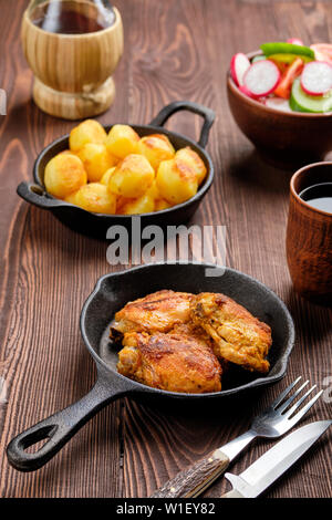 Cuisses de poulet rôties, poêlée de pommes de terre et salade - dîner rustique Banque D'Images