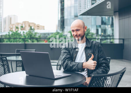 Smiling attractive succès adultes homme barbu chauve en veste noire avec coffre à café de la rue à la ville Banque D'Images