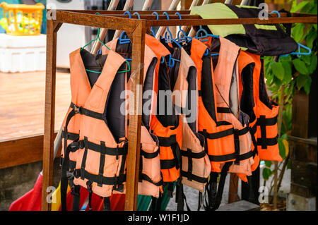 Gilets orange sur la pendaison de crémaillère en bois Banque D'Images