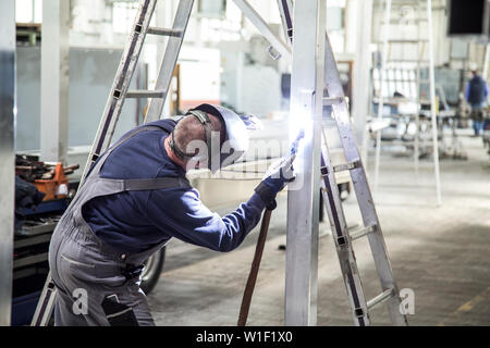 Un travailleur d'une trame de brasage pour construire quelque chose à l'intérieur d'une usine Banque D'Images