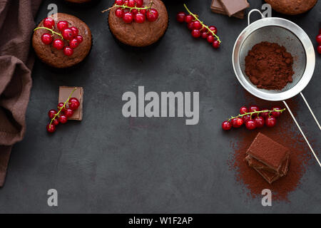 Muffins au chocolat avec châssis, barres de chocolat, de cacao et de baies sur fond de bois sombre. Vue d'en haut. Mise à plat Banque D'Images