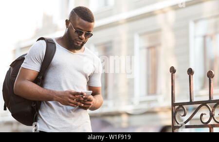 Portrait of African man with backpack textmessaging Banque D'Images