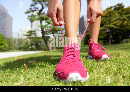 Runner se préparer pour lier des chaussures de course jogging lacets - femme préparant avant d'exécuter la mise sur les formateurs de parc japonais près de Ginza à Tokyo, Japon Banque D'Images