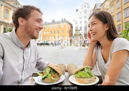 Couple eating food at Cafe à Stockholm, Suède, Europe. Jeune couple multiracial heureux à l'extérieur sur Stortorget grande place à Gamla Stan, la vieille ville de Stockholm. Homme Femme asiatique, scandinave. Banque D'Images