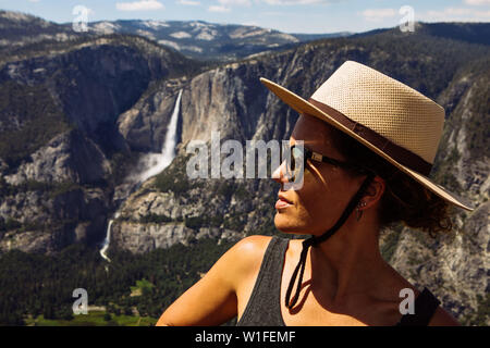 caucasien touristique 30 ans profil de femme avec un chapeau et des nuances posant avec les chutes de Yosemite dans le parc national de Glaciar point Yosemite, Californie, Etats-Unis Banque D'Images