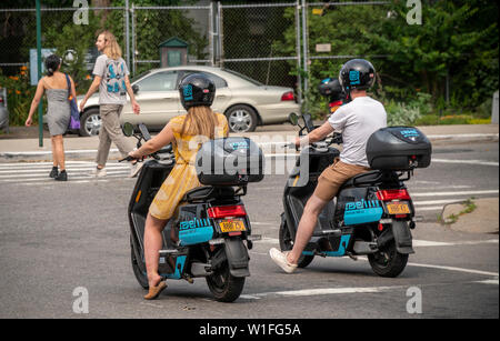 Les cavaliers sur un cyclomoteur électrique à partir de l'entreprise partage de cyclomoteurs Revel dans le quartier Red Hook de Brooklyn à New York le samedi, Juin 29, 2019. Revel Transit a récemment annoncé une expansion de leur flotte d'un modeste 68 à 1000 cyclomoteurs étendre plus loin dans Brooklyn et Queens. (© Richard B. Levine) Banque D'Images