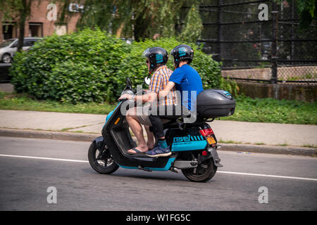 Les cavaliers sur un cyclomoteur électrique à partir de l'entreprise partage de cyclomoteurs Revel dans le quartier Red Hook de Brooklyn à New York le samedi, Juin 29, 2019. Revel Transit a récemment annoncé une expansion de leur flotte d'un modeste 68 à 1000 cyclomoteurs étendre plus loin dans Brooklyn et Queens. (© Richard B. Levine) Banque D'Images