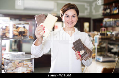 Smiling girl décider sur la meilleure barre de chocolat en pâtisserie Banque D'Images